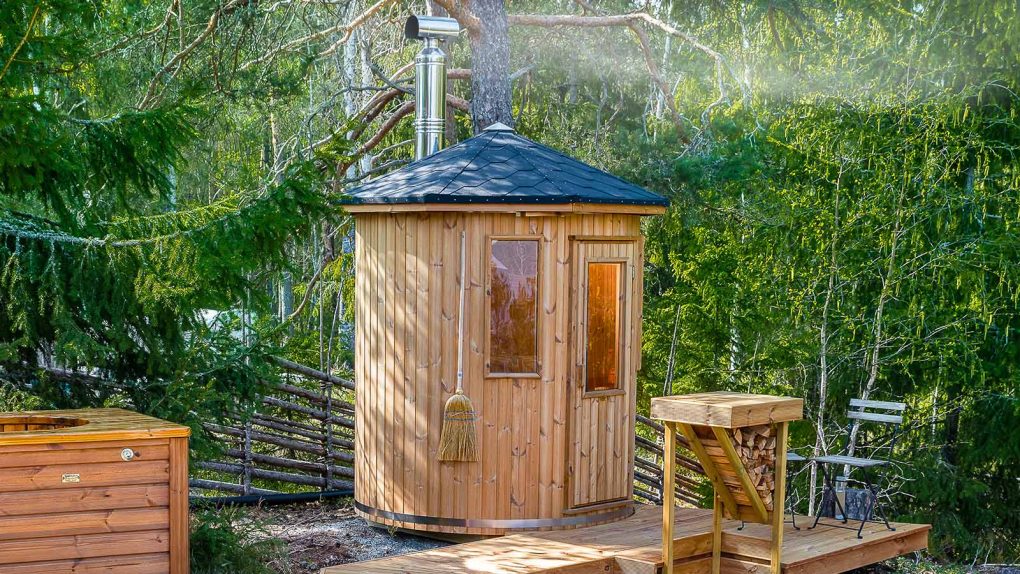 Sauna tonneau en bois entouré d'arbres