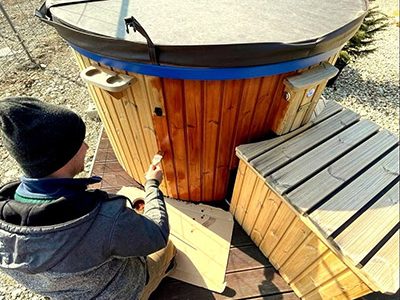 Homme qui lasure son bain nordique