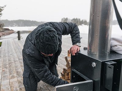 Homme qui alimente le poêle d'un bain nordique